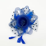 A royal blue fascinator hair accessory featuring a layered mesh flower, polka-dotted tulle, feathers, and tassels, photographed on a clean white background.