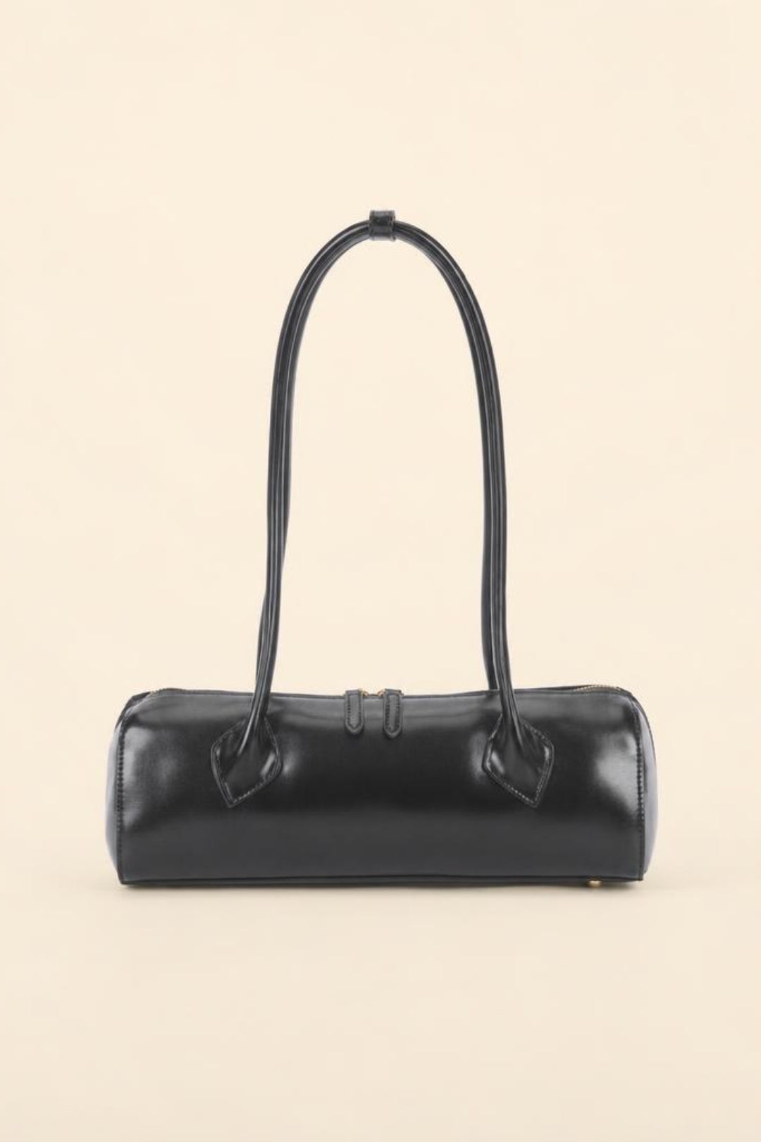 A black leather cylindrical handbag with a single top handle, photographed against a solid light beige background.
