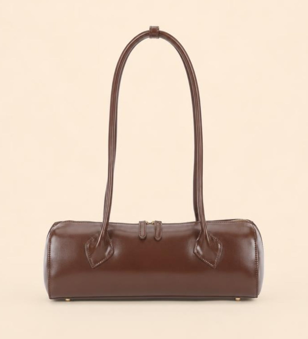 A dark brown leather cylindrical handbag with a single shoulder strap, photographed against a solid light beige background.