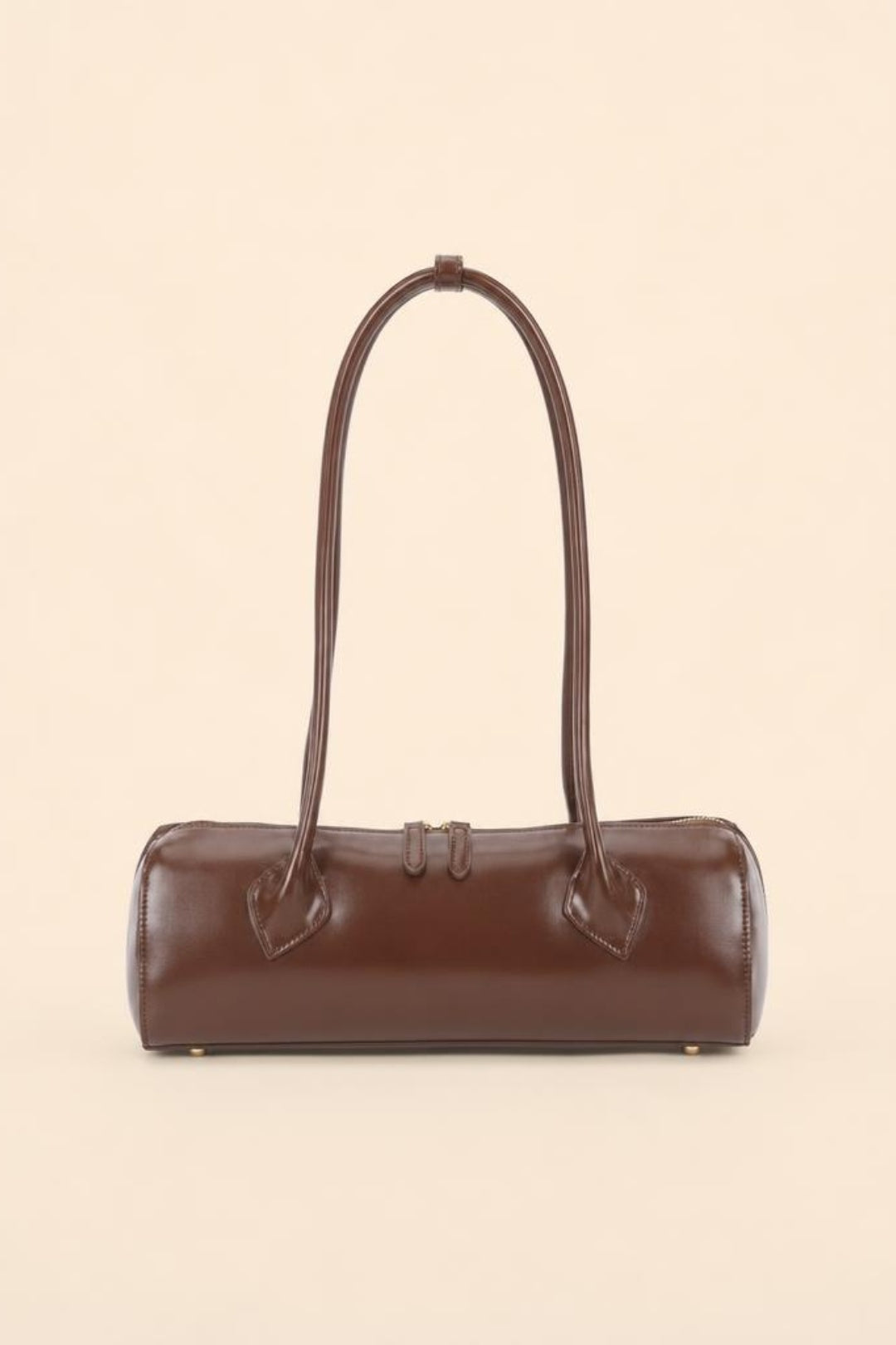 A dark brown leather cylindrical handbag with a single shoulder strap, photographed against a solid light beige background.